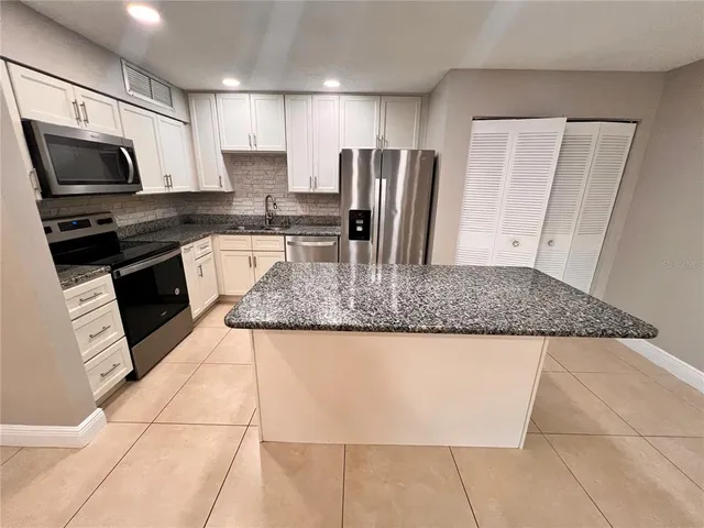 a kitchen with granite countertop a stove a sink and a microwave