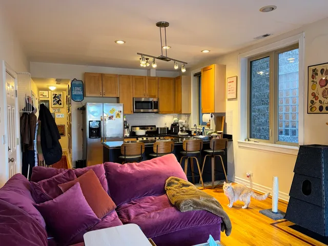 a living room with furniture kitchen view and a large window