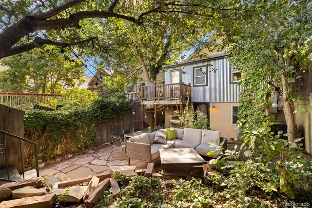 a view of a patio with couches table and chairs under an umbrella