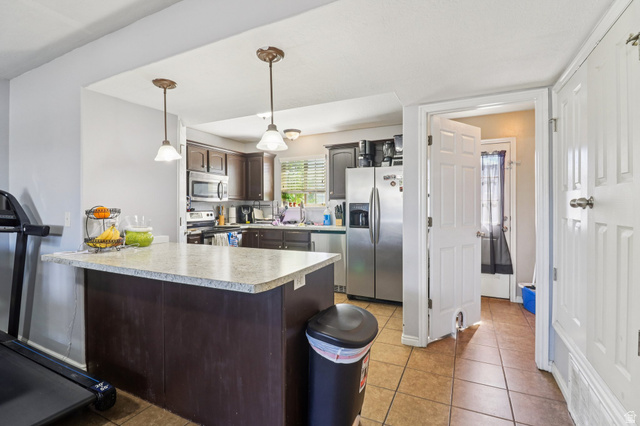 1077 South 1850th Street West Springville, UT 84663 - Photo 8 of 22 Kitchen with a peninsula, decorative light fixtures, light countertops, stainless steel appliances, and dark wood finish cabinets