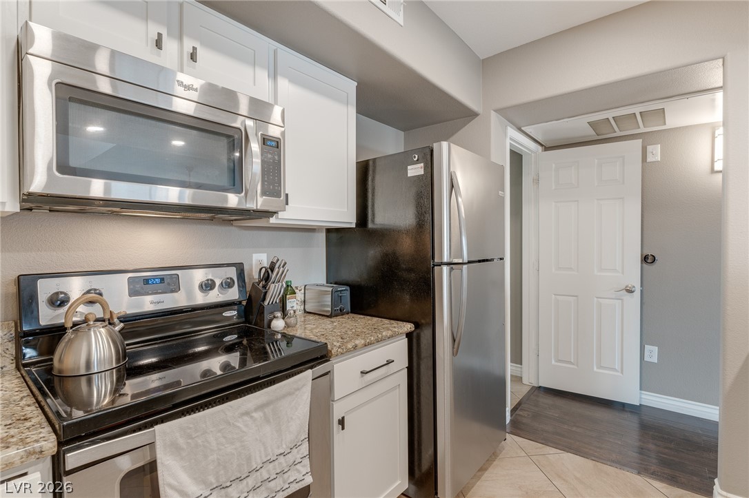 7255 West Sunset Road, Unit 2155 Las Vegas, NV 89113 - Photo 12 of 21 Kitchen with stainless steel appliances, white cabinets, light stone countertops, and light tile patterned flooring
