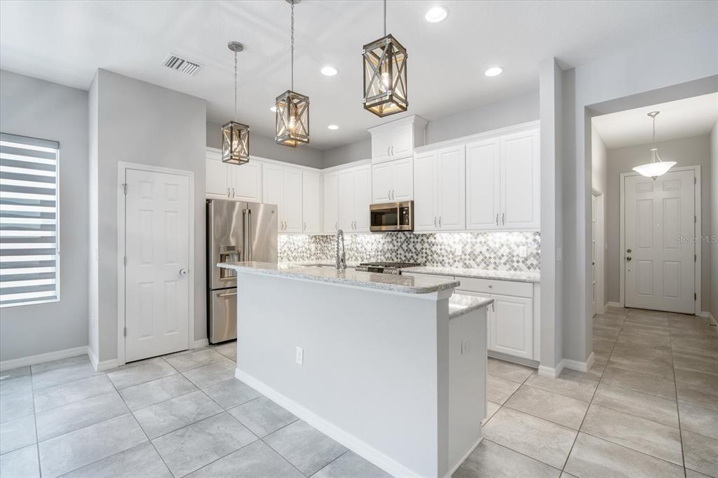 6523 Watson Road Riverview, FL 33578 - Photo 6 of 32 a kitchen with stainless steel appliances granite countertop a refrigerator a stove oven and white cabinets with wooden floor