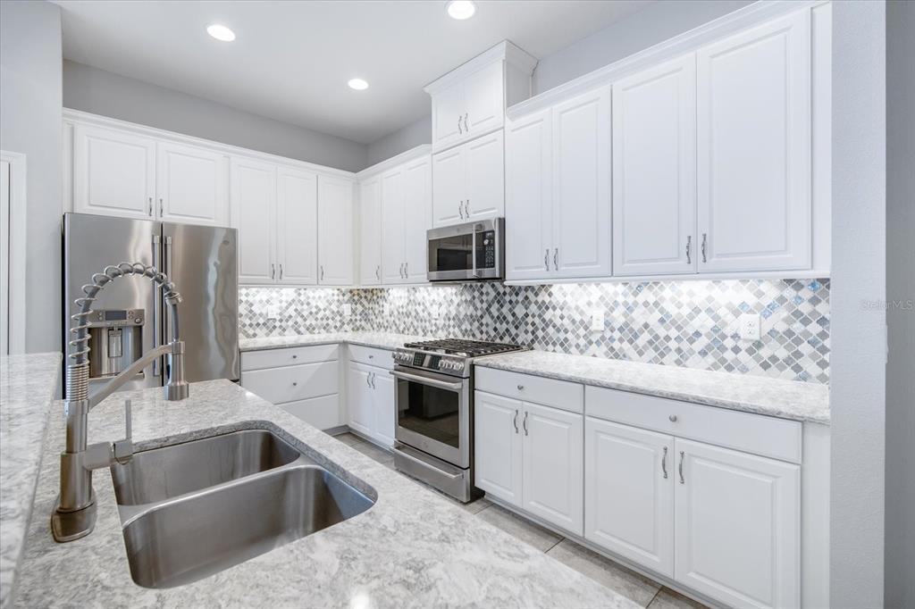 6523 Watson Road Riverview, FL 33578 - Photo 7 of 32 a kitchen with granite countertop a sink stainless steel appliances and white cabinets