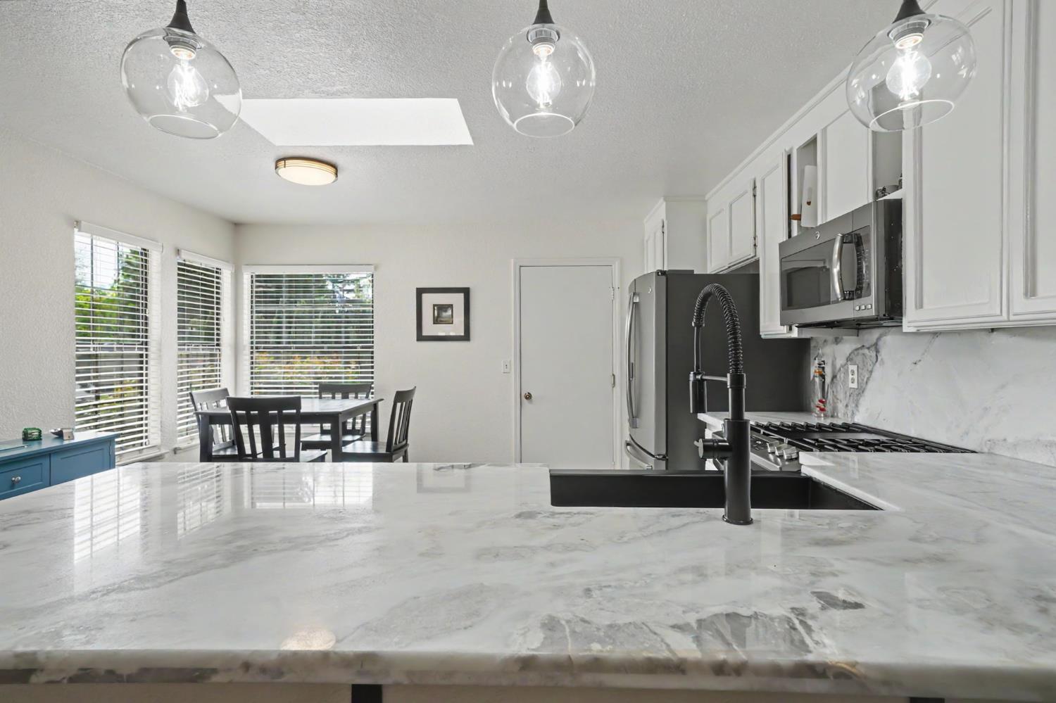 67 St Andrews Road Valley Springs, CA 95252 - Photo 15 of 58 a kitchen with stainless steel appliances granite countertop a stove refrigerator a dining table and chairs with wooden floor