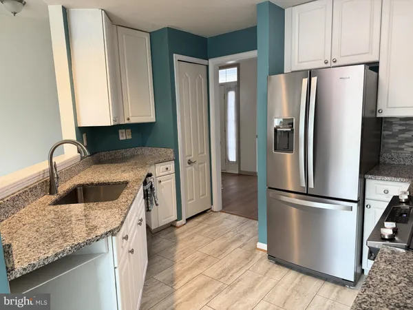 a kitchen with granite countertop a refrigerator and a sink