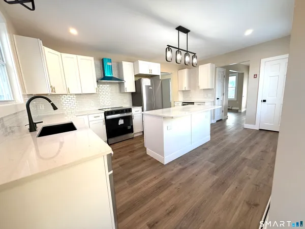 a kitchen that has a lot of cabinets a sink and appliances
