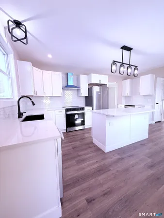 a large kitchen with kitchen island a stove a sink wooden floor and cabinets