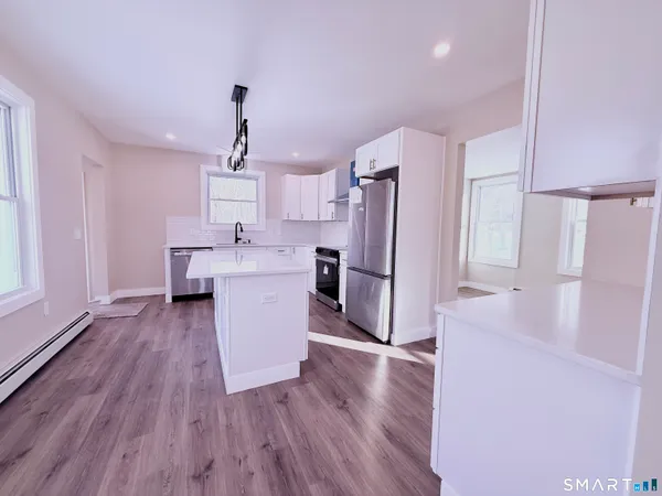 a kitchen with stainless steel appliances a refrigerator a sink dishwasher and a stove with wooden floors