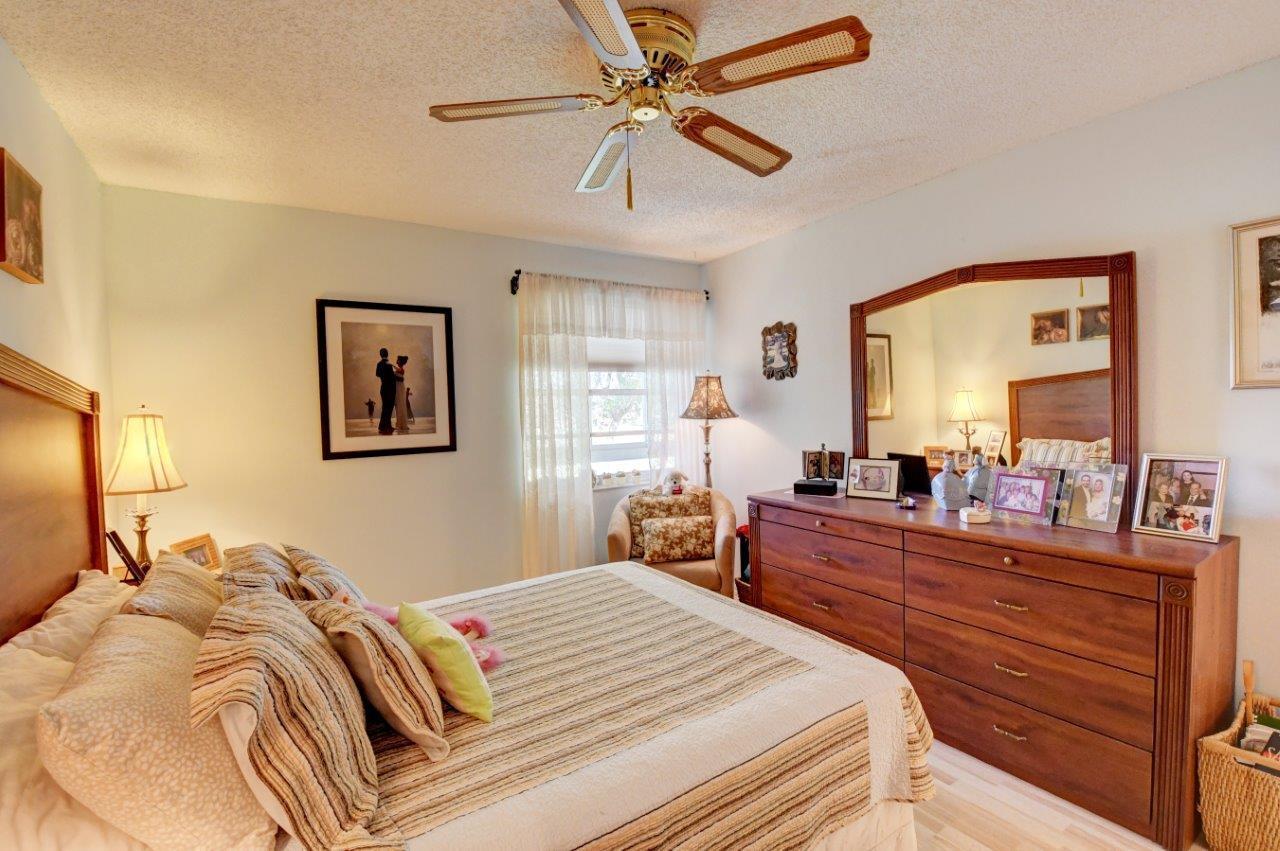 369 Capri H Delray Beach, FL 33484 - Photo 17 of 25 a bedroom with a bed and a chandelier