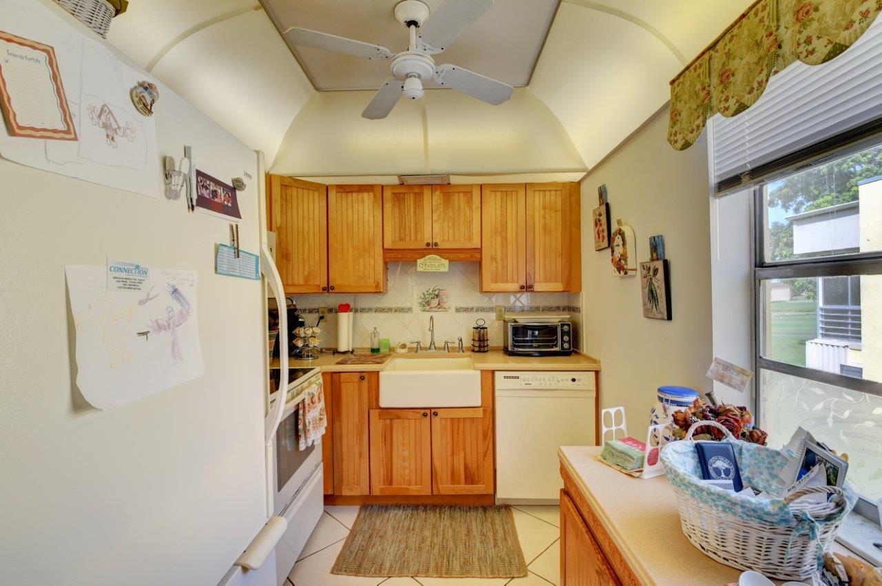 369 Capri H Delray Beach, FL 33484 - Photo 7 of 25 a kitchen with stainless steel appliances a stove a refrigerator cabinets and a dining table
