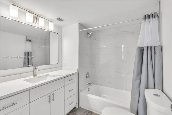 a bathroom with a tub shower sink vanity and a toilet