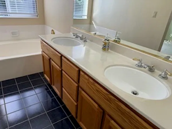 a bathroom with a double vanity sink a mirror and a bathtub