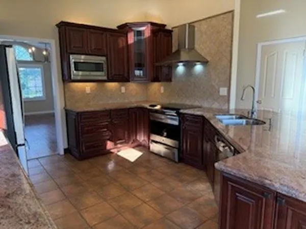 a kitchen with stainless steel appliances granite countertop a stove a sink and a microwave
