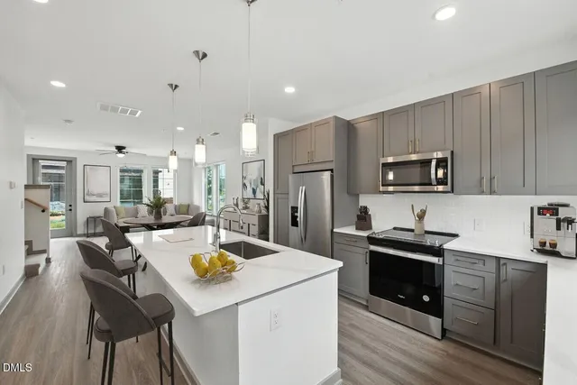 a kitchen with a refrigerator a stove microwave oven with white cabinets and wooden floor