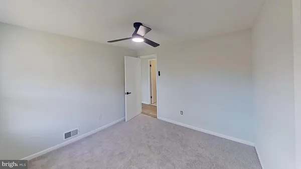 an empty room with a ceiling fan and carpet