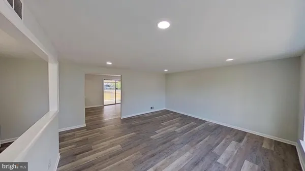 a view of an empty room with wooden floor and window