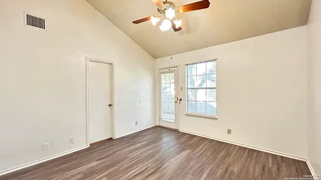 a view of an empty room with wooden floor and a window