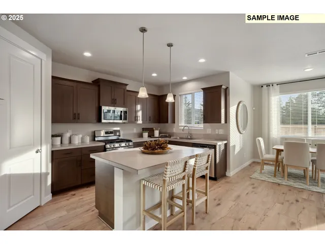 a kitchen with stainless steel appliances granite countertop a stove a sink a refrigerator a dining table and chairs