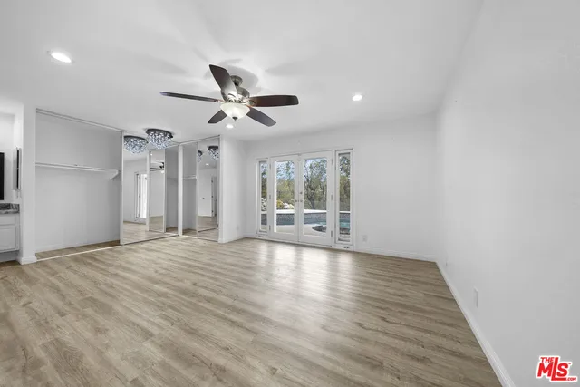 a view of an empty room with a window and wooden floor