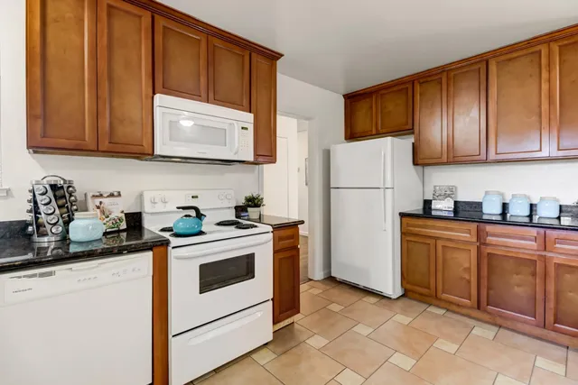 a kitchen with granite countertop a refrigerator stove top oven and sink