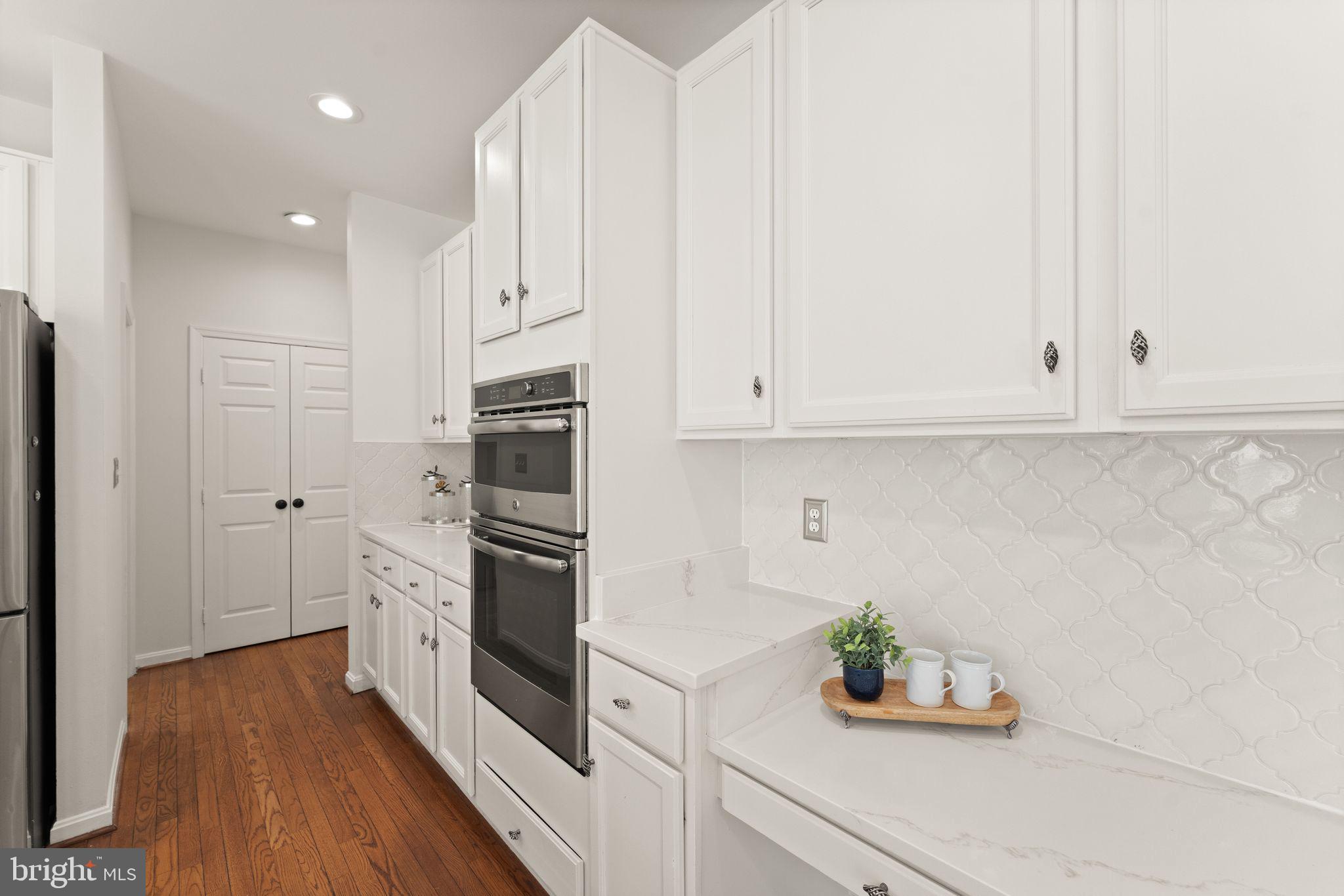 43179 Parkers Ridge Drive Leesburg, VA 20176 - Photo 39 of 108 a kitchen with stainless steel appliances white cabinets and wooden floor