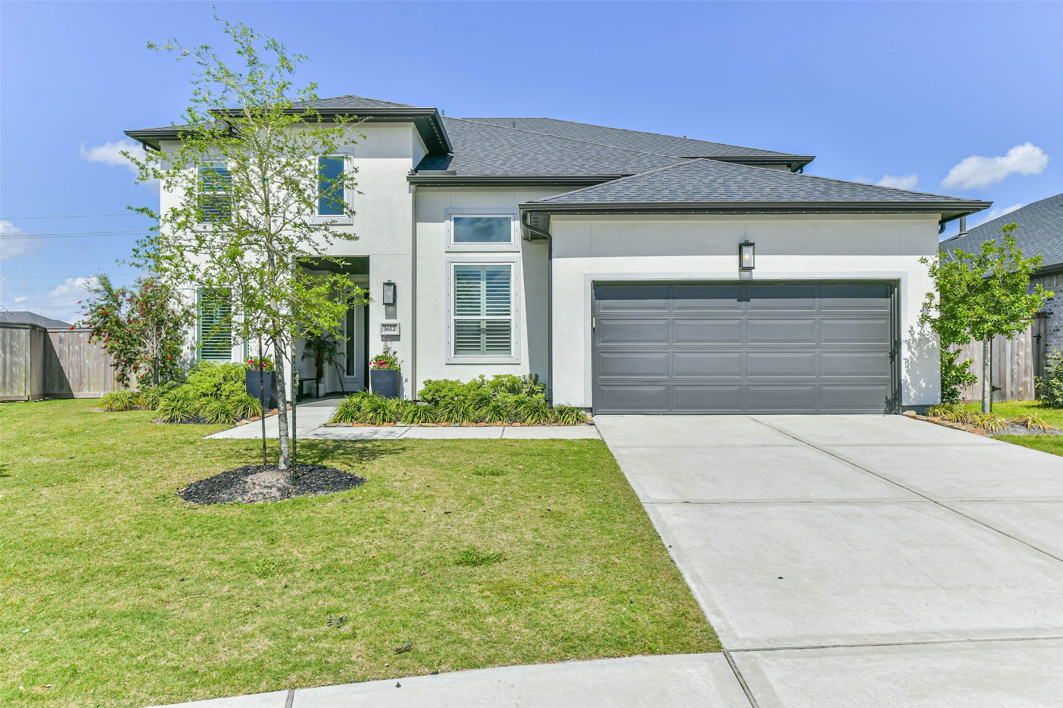 1612 Dayton Rdg Circle Friendswood, TX 77546 - Photo 5 of 50 This modern two-story home features a sleek gray and white exterior, large windows with shutters, and a spacious double garage. The well-maintained lawn and landscaped garden enhance its curb appeal.