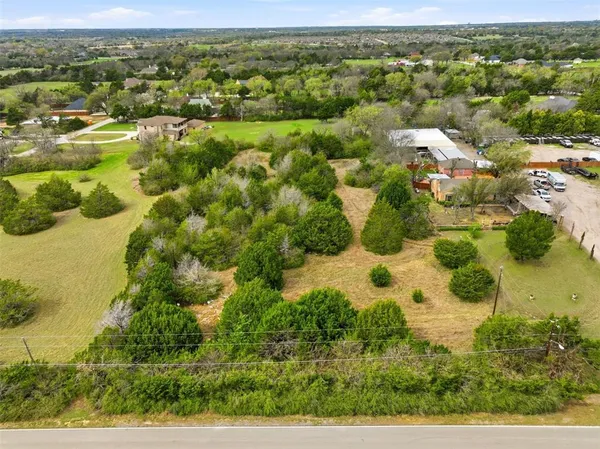an aerial view of residential houses with outdoor space and trees