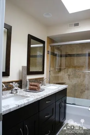 a bathroom with a sink double vanity granite and a mirror