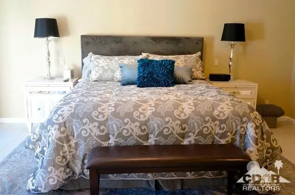 a bedroom with a bed and a lamp on dresser
