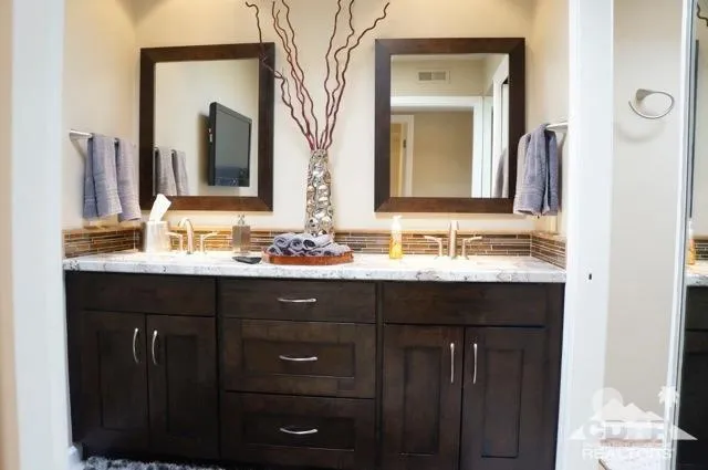 a en suite bathroom with a granite countertop sink and a mirror