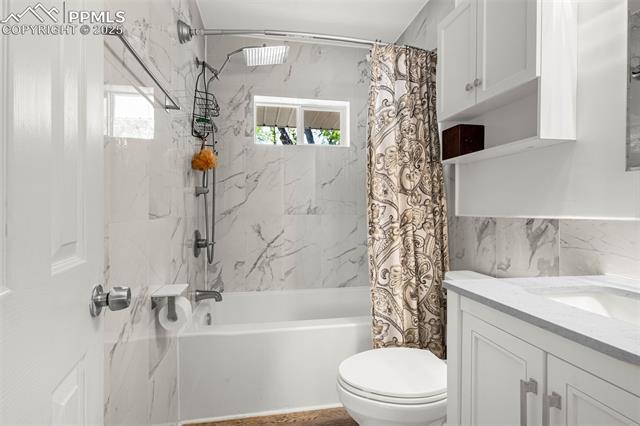 605 Huron Road Colorado Springs, CO 80910 - Photo 13 of 30 Full bathroom with shower / tub combo, toilet, healthy amount of natural light, vanity, and tile walls