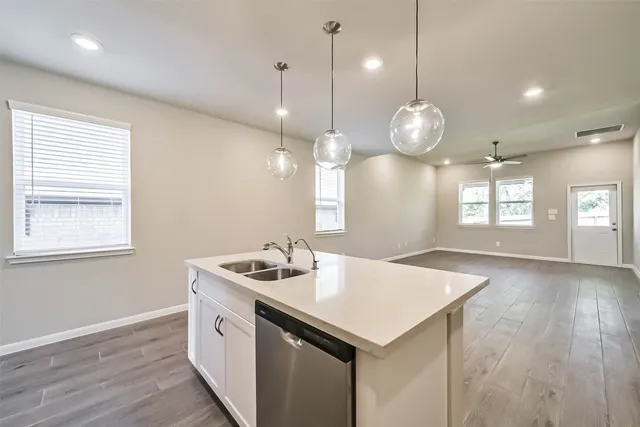 a kitchen with a sink chandelier and wooden floor