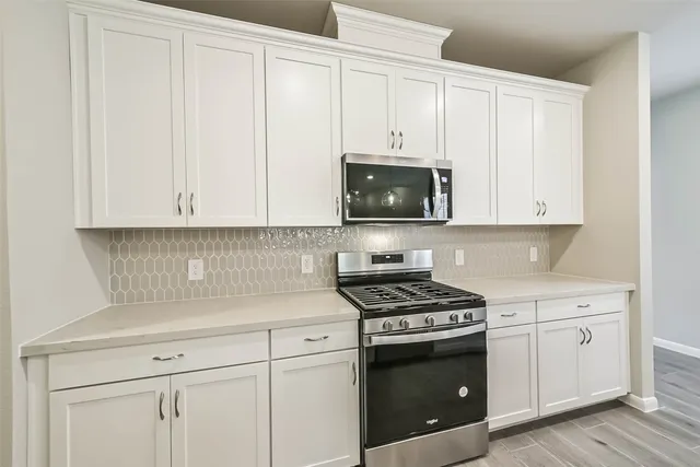 a kitchen with granite countertop white cabinets and stainless steel appliances
