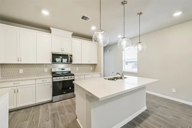 a kitchen with stainless steel appliances granite countertop a sink a stove and a wooden floors