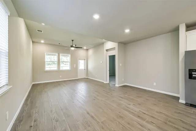 an empty room with wooden floor and windows