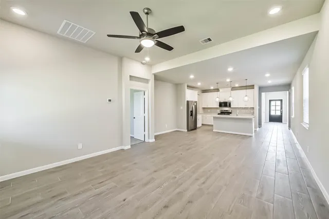 a view of a livingroom with a ceiling fan wooden floor and a ceiling fan