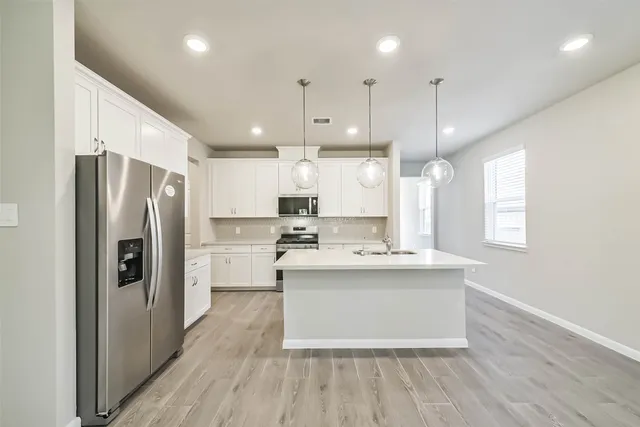 a kitchen with kitchen island white cabinets and stainless steel appliances