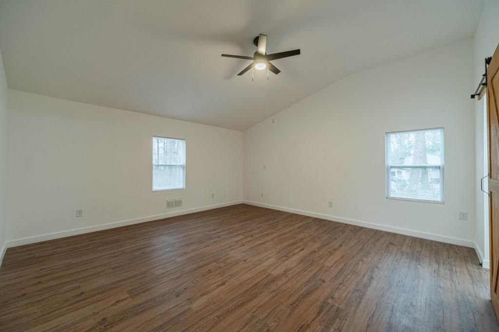 3617 Bob White Lane Southwest Loganville, GA 30052 - Photo 19 of 48 an empty room with wooden floor chandelier fan and windows