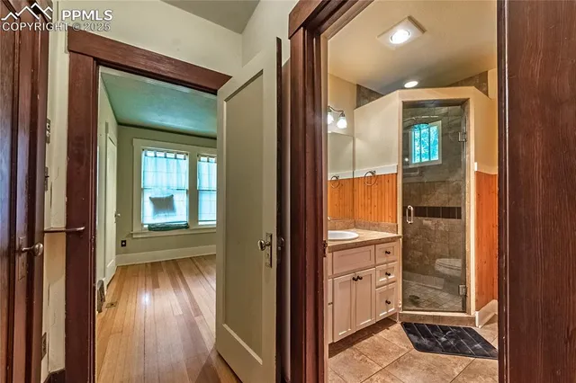 an empty room with wooden floor mirror and windows