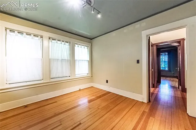 a view of an empty room with wooden floor and a window