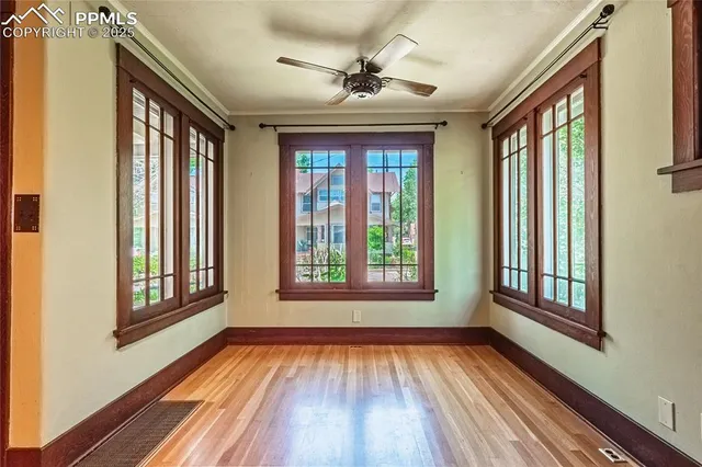 a view of an empty room with wooden floor and a window