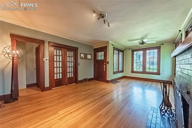 a view of an empty room with wooden floor and a window