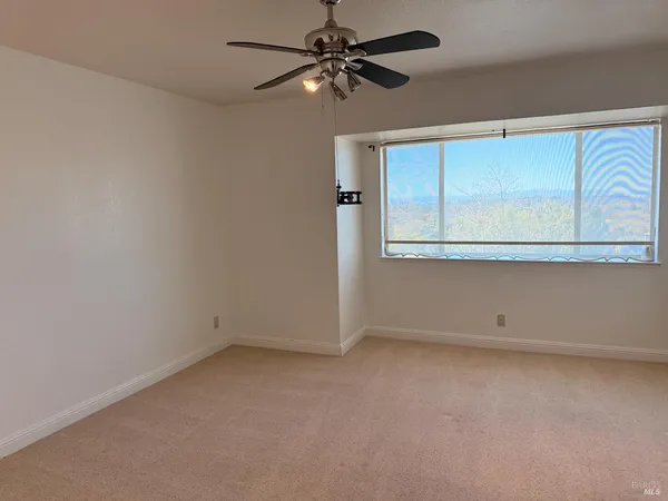 an empty room with a window and ceiling fan