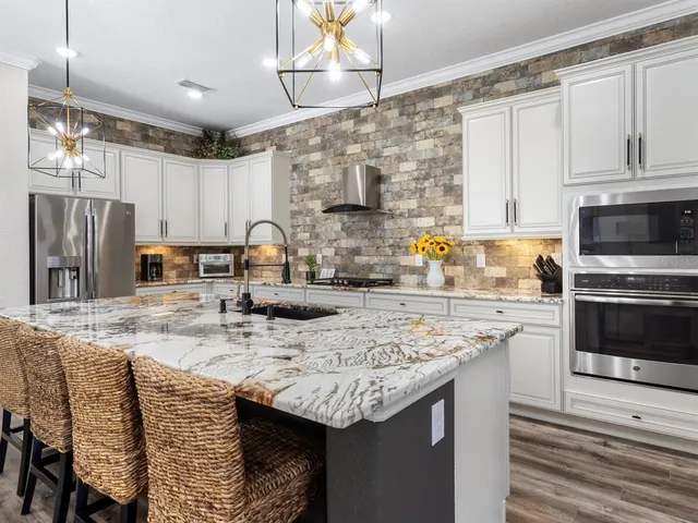 a kitchen with stainless steel appliances granite countertop stove a table and chairs in it