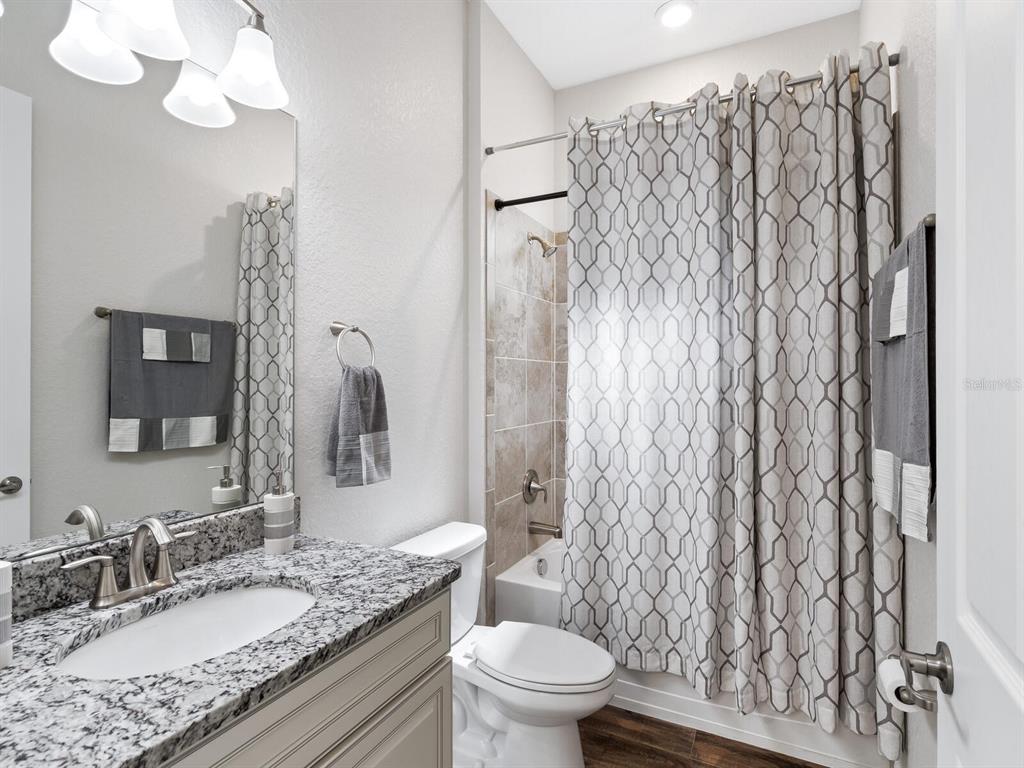 16532 Hillside Circle Lakewood Ranch, FL 34202 - Photo 28 of 67 a bathroom with a granite countertop sink a toilet and shower curtain