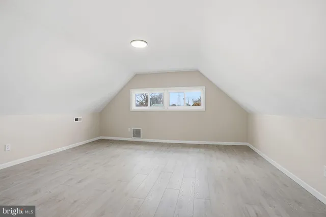 a view of an empty room with wooden floor and windows