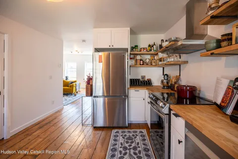 a kitchen with stainless steel appliances granite countertop a refrigerator a stove a sink and white cabinets with wooden floor