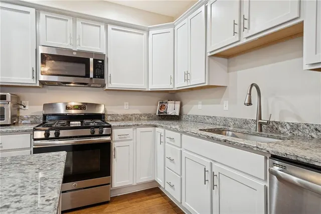 a kitchen with granite countertop white cabinets and stainless steel appliances