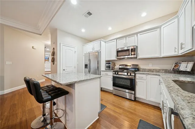 a kitchen with stainless steel appliances a stove a sink cabinets and a dining table
