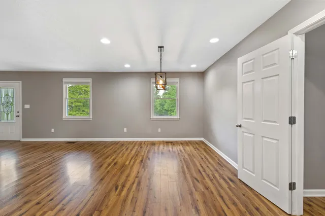an empty room with wooden floor windows and exposed bricks